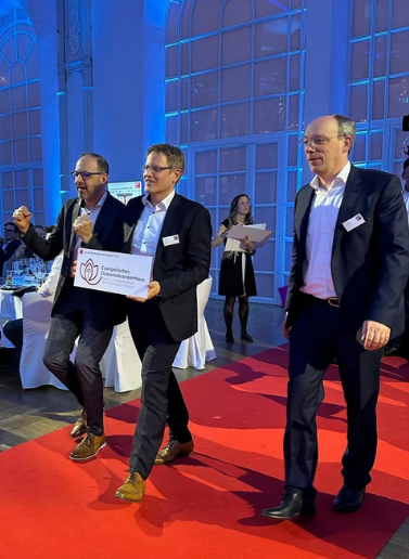 Matthias Jenny (Vorstand und Pflegedirektor), Michael Decker (Vorstandsvorsitzender) und Pfr. Dr. Björn Slenczka (Theologischer Vorstand) auf dem roten Teppich unmittelbar vor Übergabe der Auszeichnung. Matthias Jenny (Vorstand und Pflegedirektor), Michael Decker (Vorstandsvorsitzender) und Pfr. Dr. Björn Slenczka (Theologischer Vorstand) auf dem roten Teppich unmittelbar vor Übergabe der Auszeichnung.